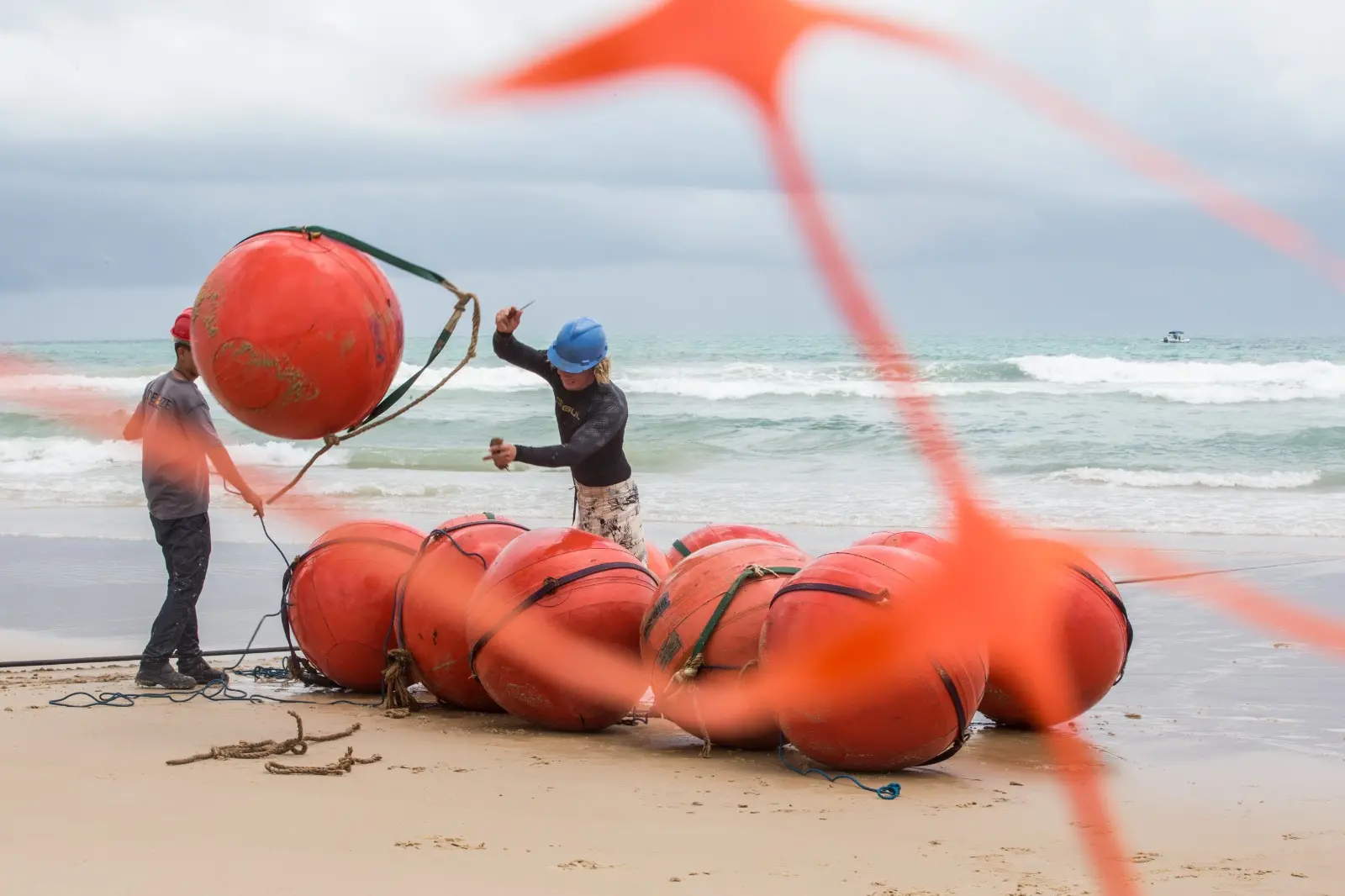 Trabalhadores tirando boias que demarcavam caminho de cabo de fibra ótica na Praia do Futuro.