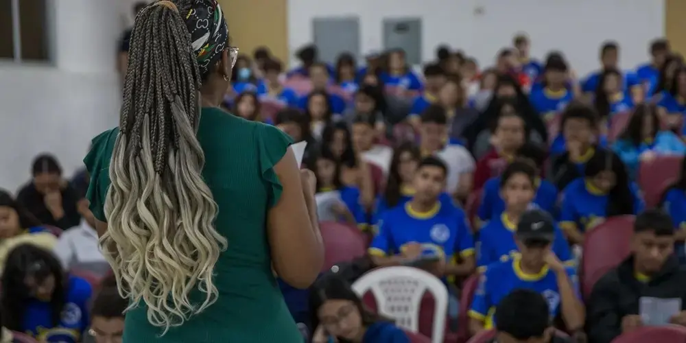 pessoa de costas diante de grupo, que traja farda azul.