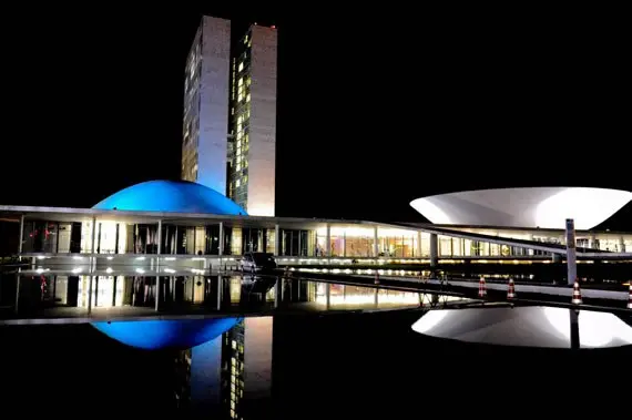 Estrutura do Congresso Nacional à noite, com luzes brancas e azuis.