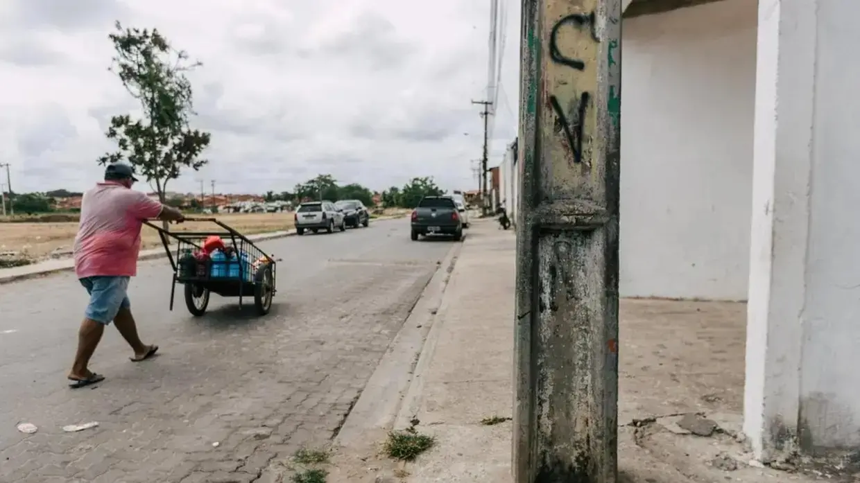 Visão de rua em bairro de Fortaleza, com destaque para poste com as iniciais CV.
