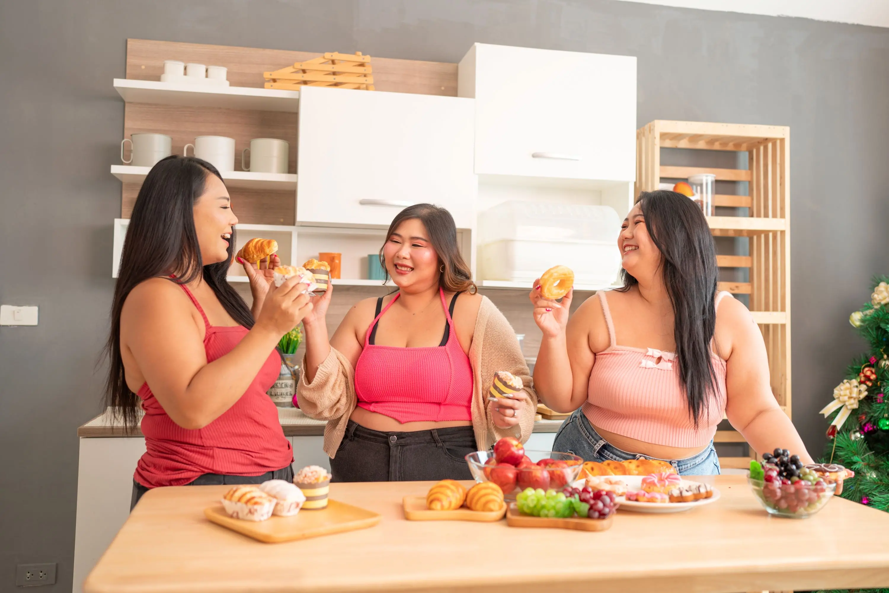 três mulheres gordas felizes, interagindo, comendo, sorrindo.