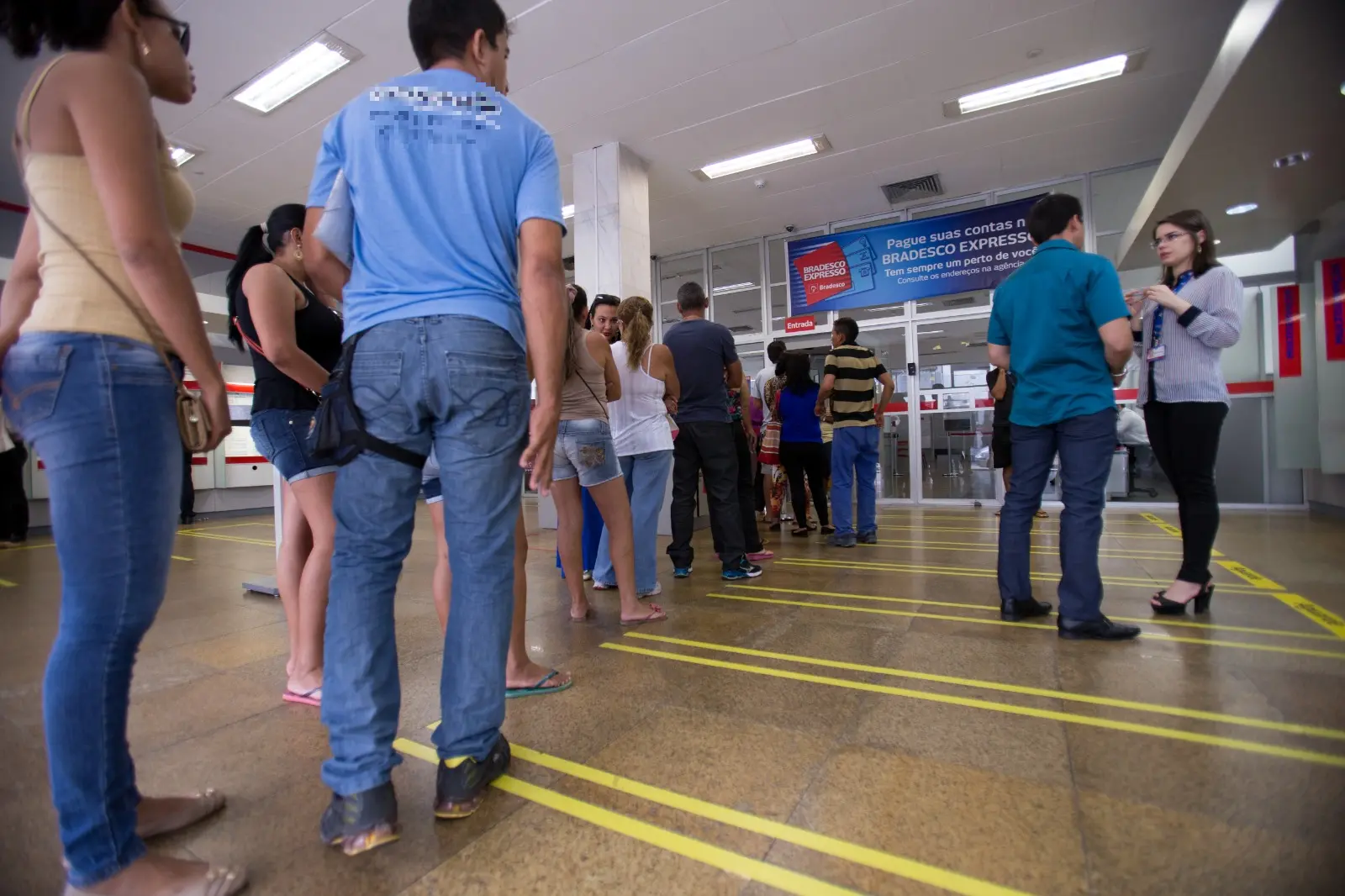 Fila de pessoas para entrar em agência bancária.