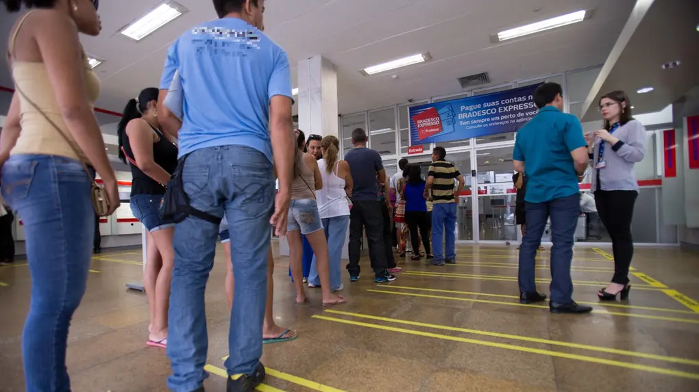 Fila de pessoas para entrar em agência bancária.