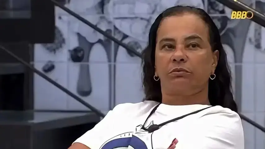 Solange é uma mulher idosa, negra, de cabelo longo castanho. Na foto, ela está com expressão séria.