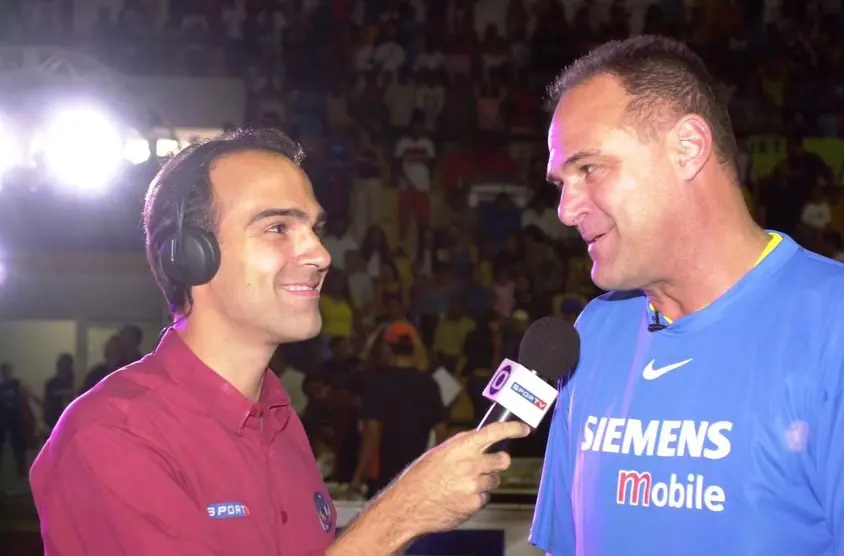 foto de Tadeu e Oscar Schmidt durante entrevista em quadra de esportes.