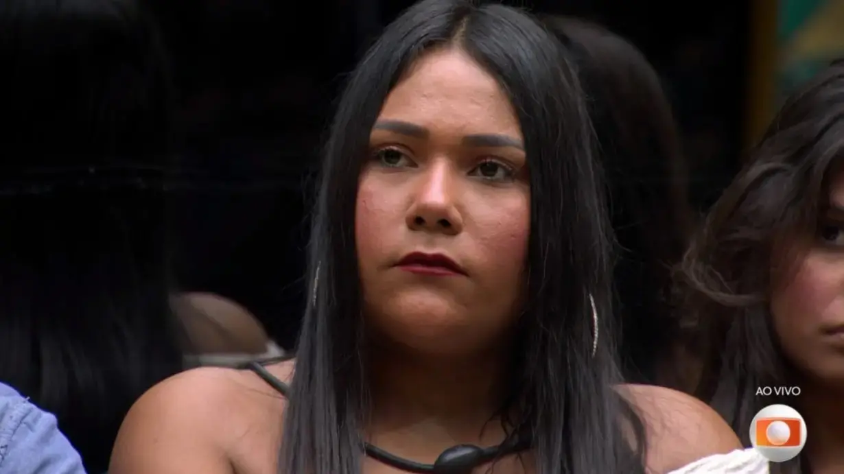 Chaiany é uma mulher negra de cabelo preto e liso. Na foto, ela está com expressão séria.