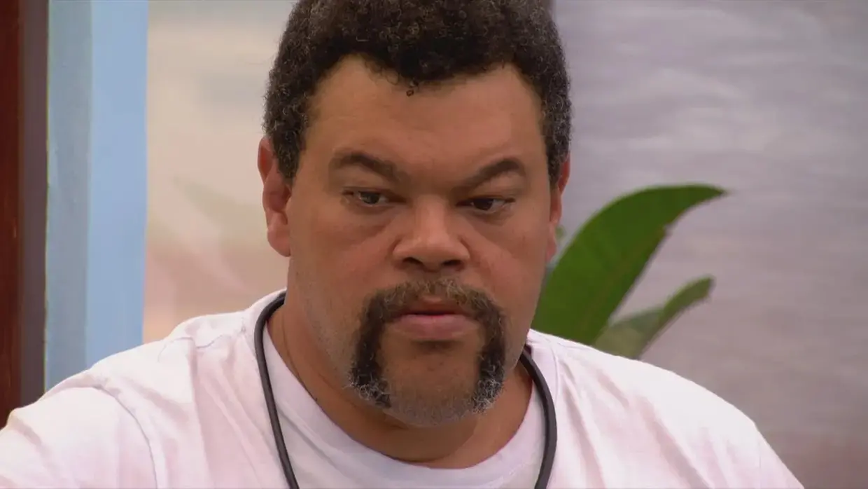 Babu é um homem de meia idade, negro, de cabelo curto e bigode em U. Na foto, ele usa camisa branca e está com expressão séria.