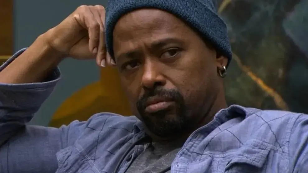 Leandro Boneco é um homem de meia idade, negro, de cavanhaque. Na foto, ele usa touca azul e está com blusa cinza e sobreposição azul.