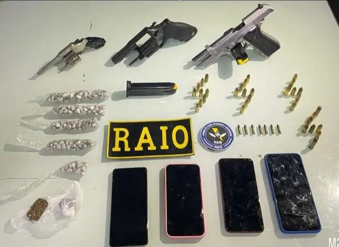 bpraio armas municoes celulares material apreendido em cima da mesa exposto.