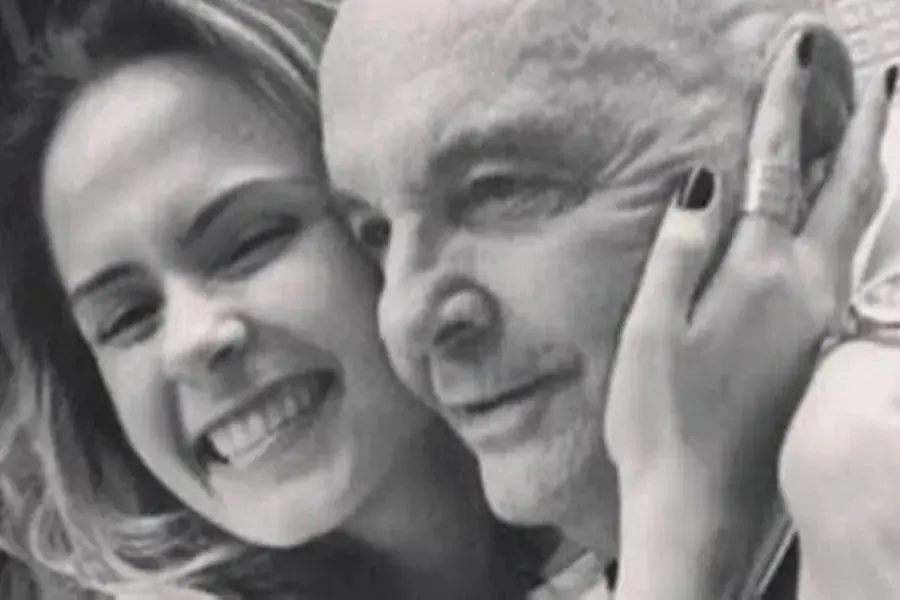 Foto em preto e branco de Ana Paula e seu pai, Gerardo. Os dois estão abraçados. Ela está sorrindo, com a mão no rosto dele.