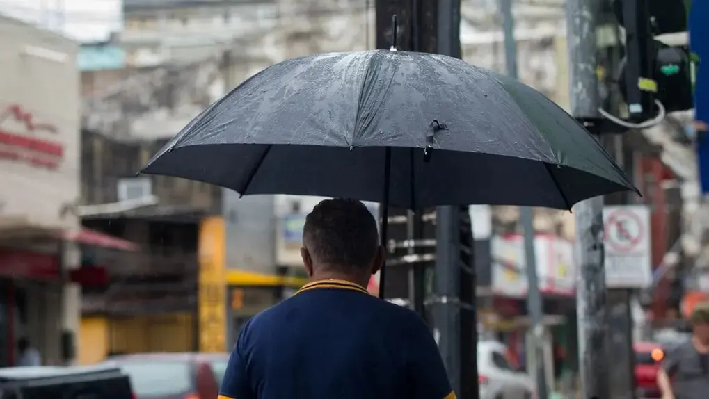 Foto de homem se protegendo da chuva.