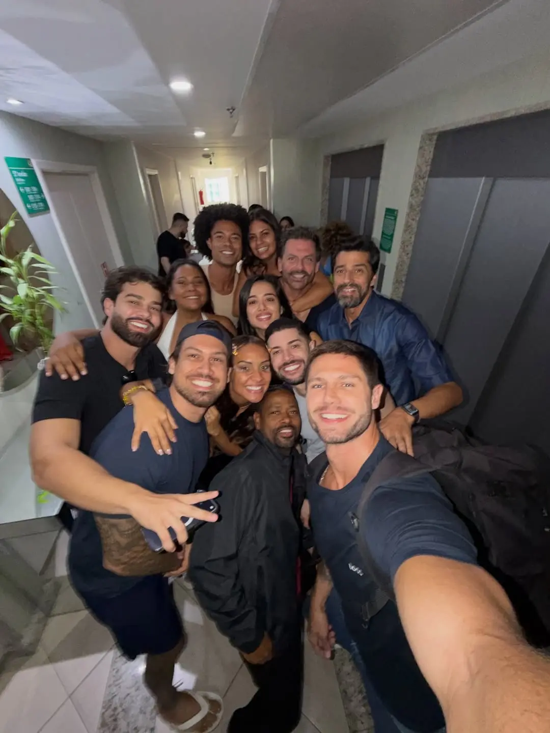 Ex-participantes eliminados do BBB 26 posam para foto sorrindo em corredor de hotel.