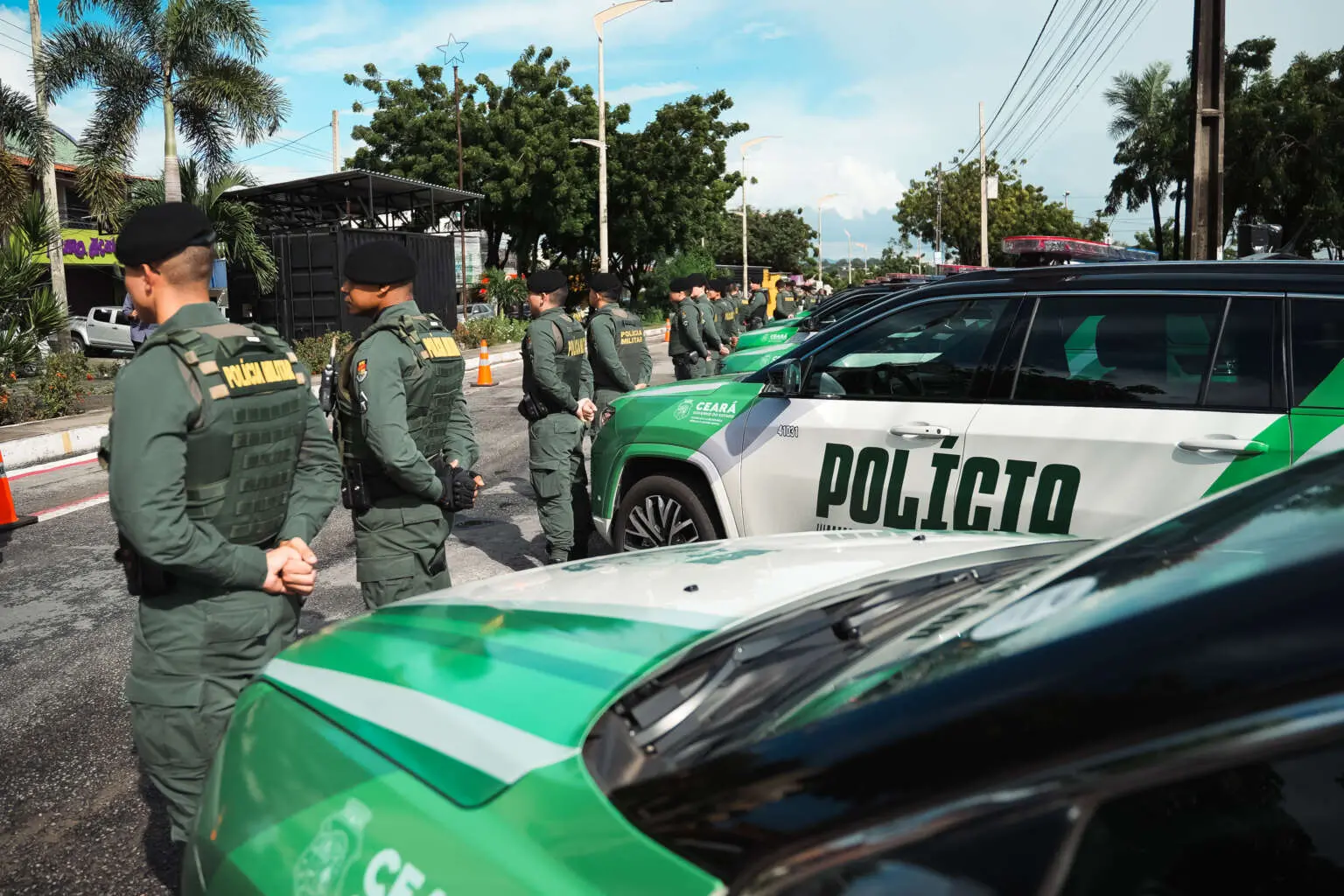 Policiais militares do Ceará em frente a viaturas.