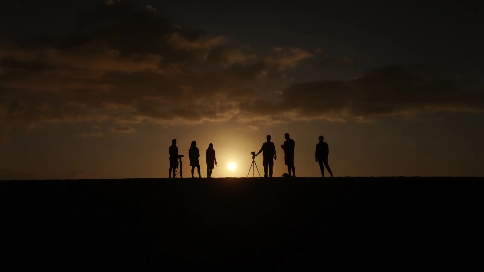Silhuetas da equipe da TV Verdes Mares em um por do sol.