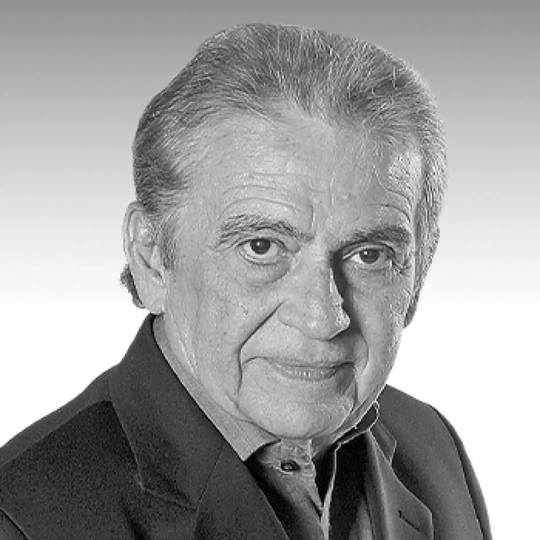 Imagem em preto e branco de um homem idoso com cabelo grisalho e expressão séria, vestindo terno e gravata, com fundo neutro.