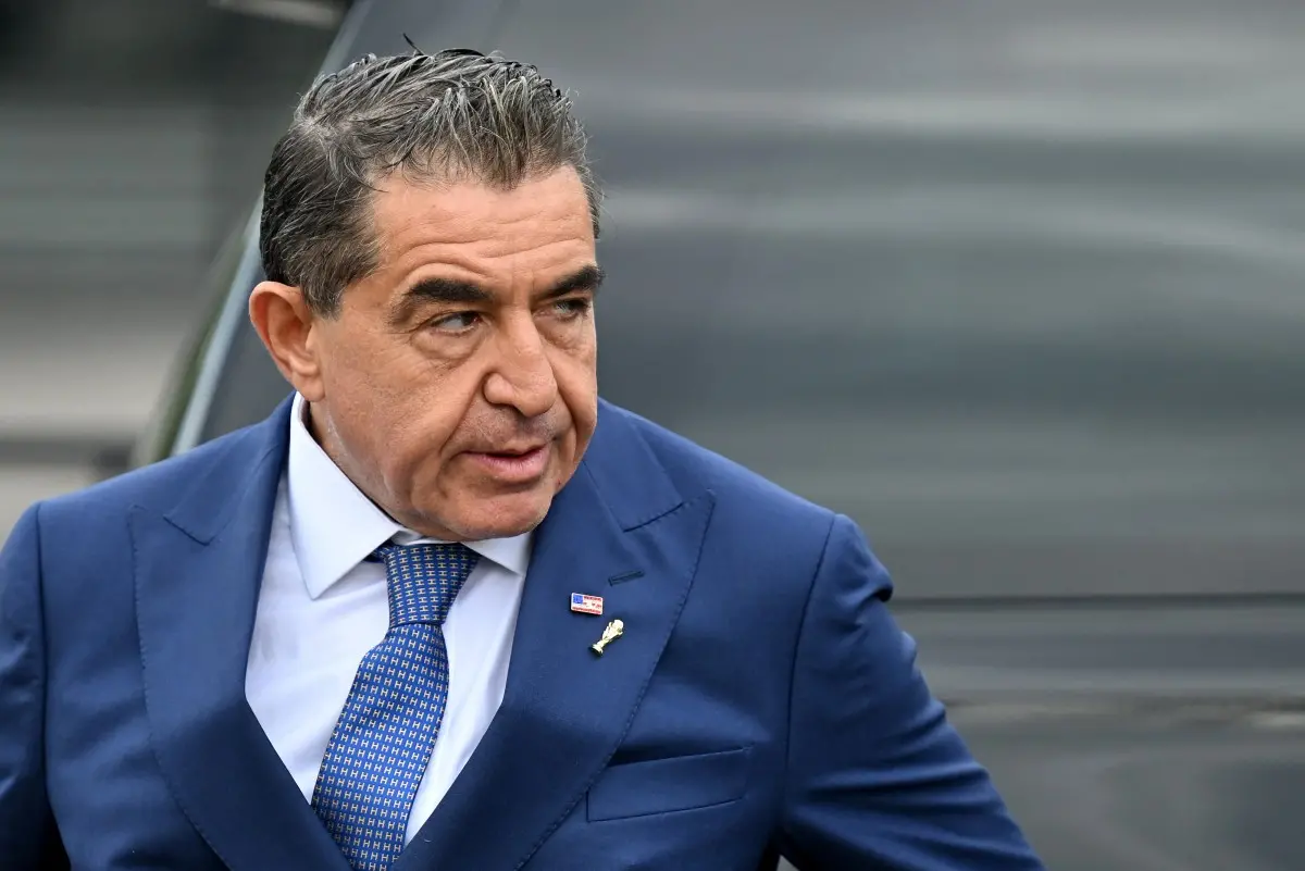 Imagem de uma pessoa de terno azul e gravata, com expressão séria, caminhando ao ar livre, com foco em sua face e traje formal.