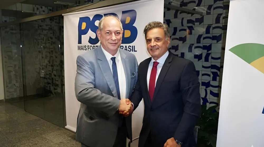 Ciro Gomes e Áecio Neves apertam as mãos, em frente a um banner do PSDB.