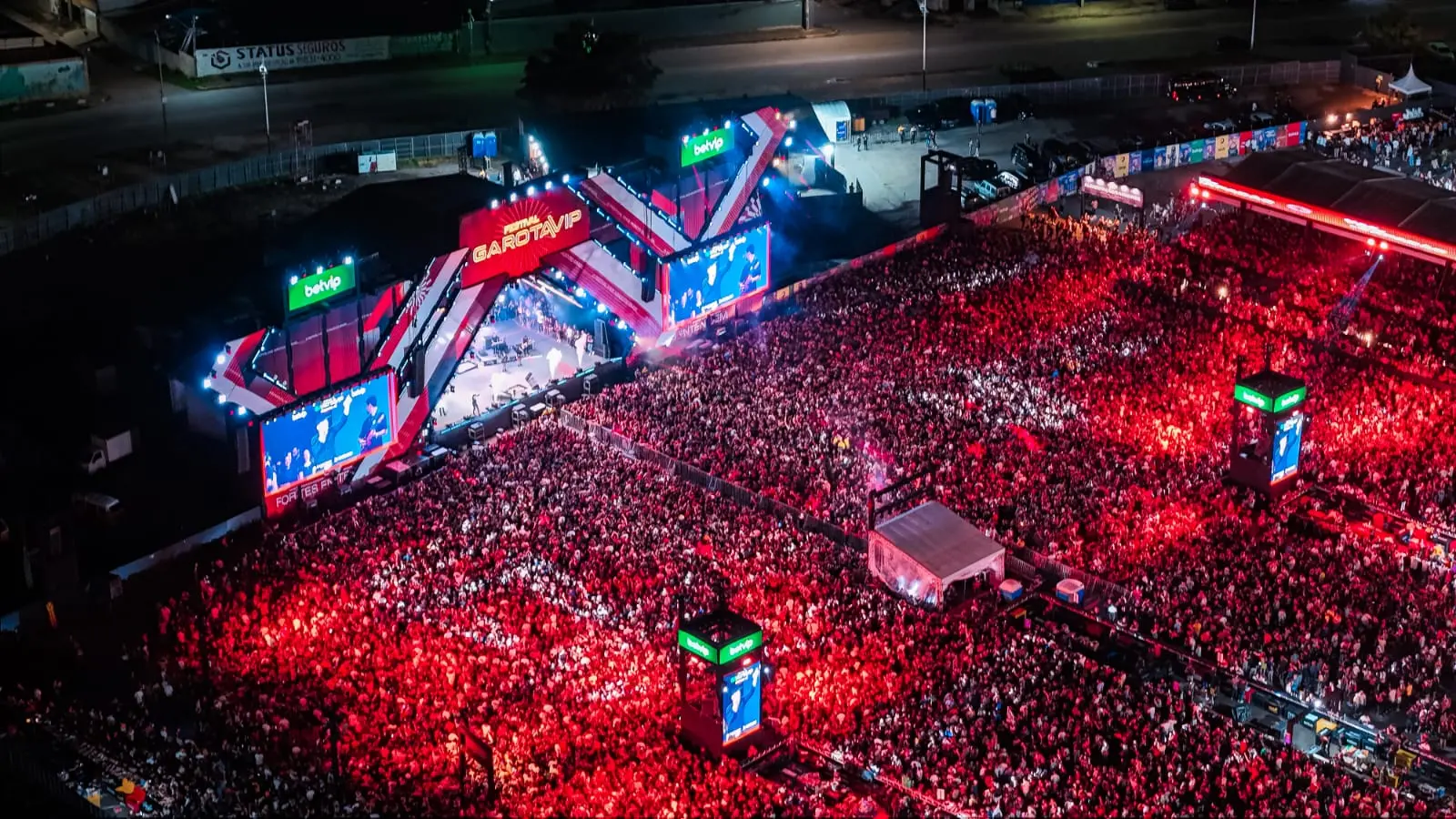 Imagem mostra palco do show Garota Vip, com multidão iluminada por luzes vermelhas.