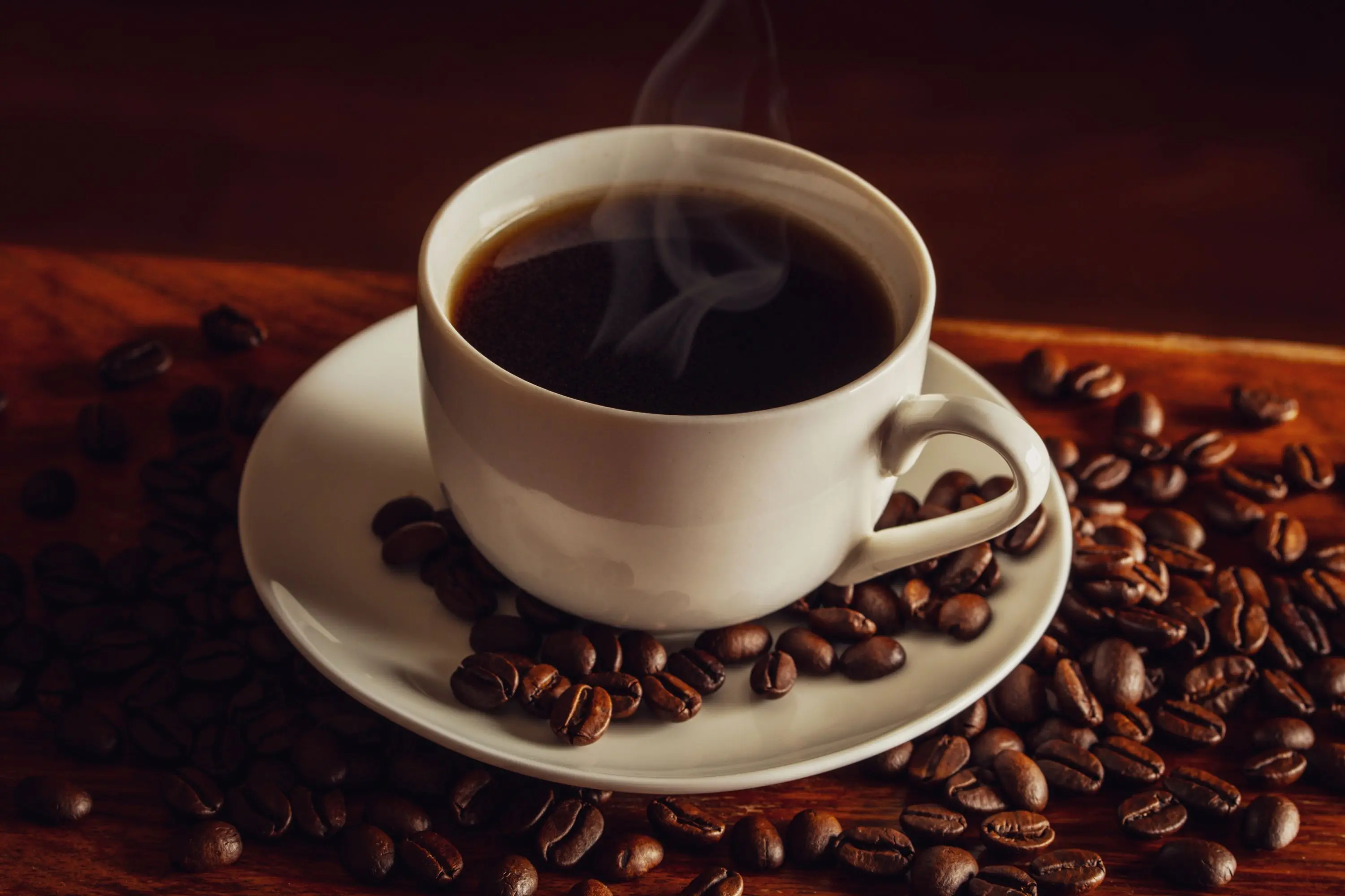 Café quente e grãos de café sobre a mesa.