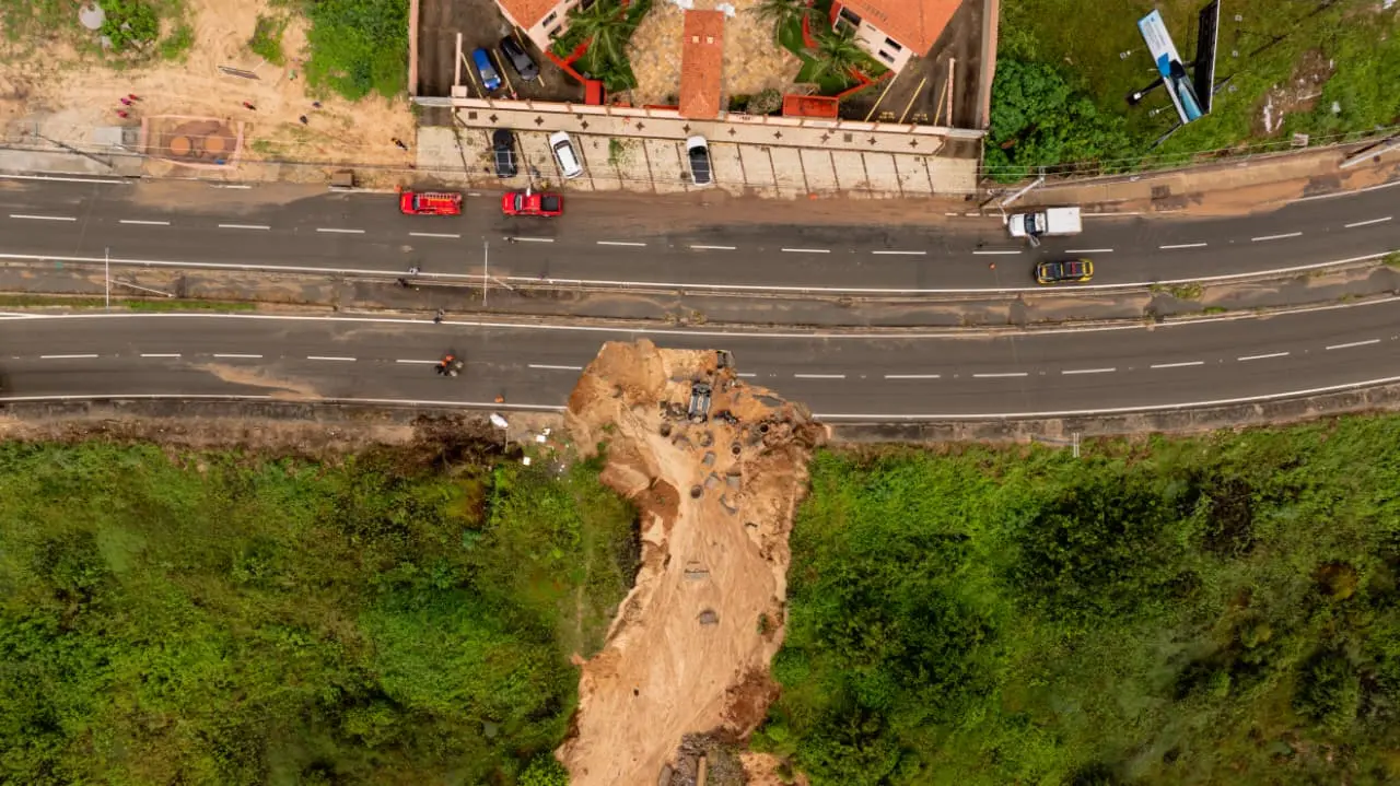 Imagem aérea mostra cratera que abriu na CE-025, em Aquiraz, na Região Metropolitana de Fortaleza. Na imagem, é possível verificar um dos três carros engolidos pelo desabamento e proximidade da fenda com condomínio.