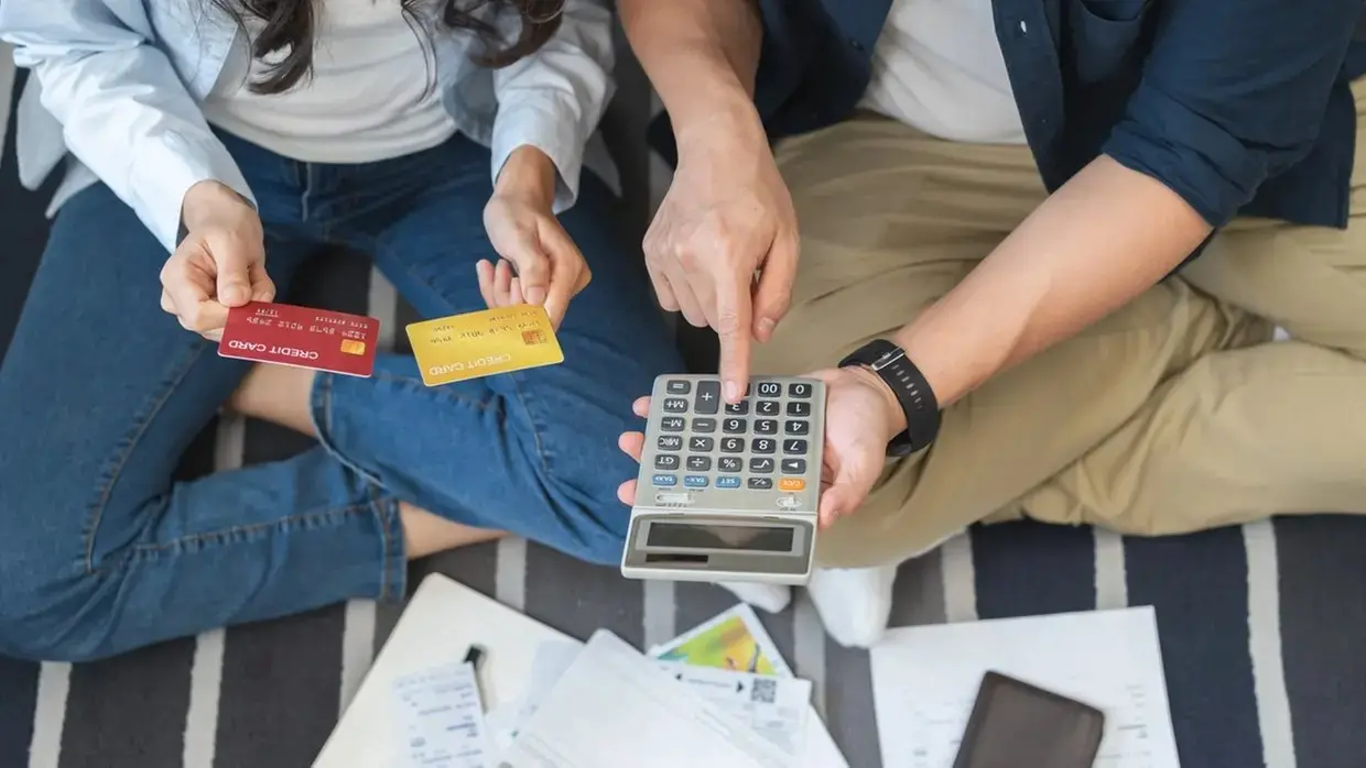 Imagem ilustrativa de pessoas usando calculadora e com cartões em mãos.