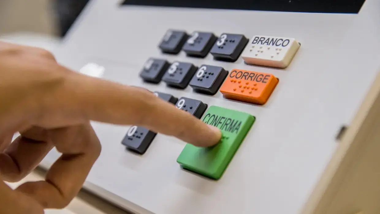 Eleitor aperta a tecla confirma na urna eletrônica.
