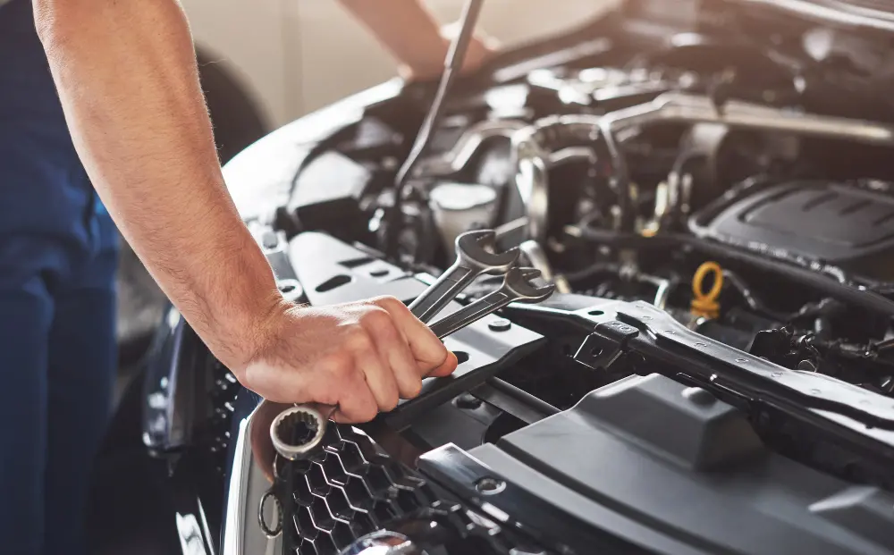 Homem branco consertando um carro em uma oficina.