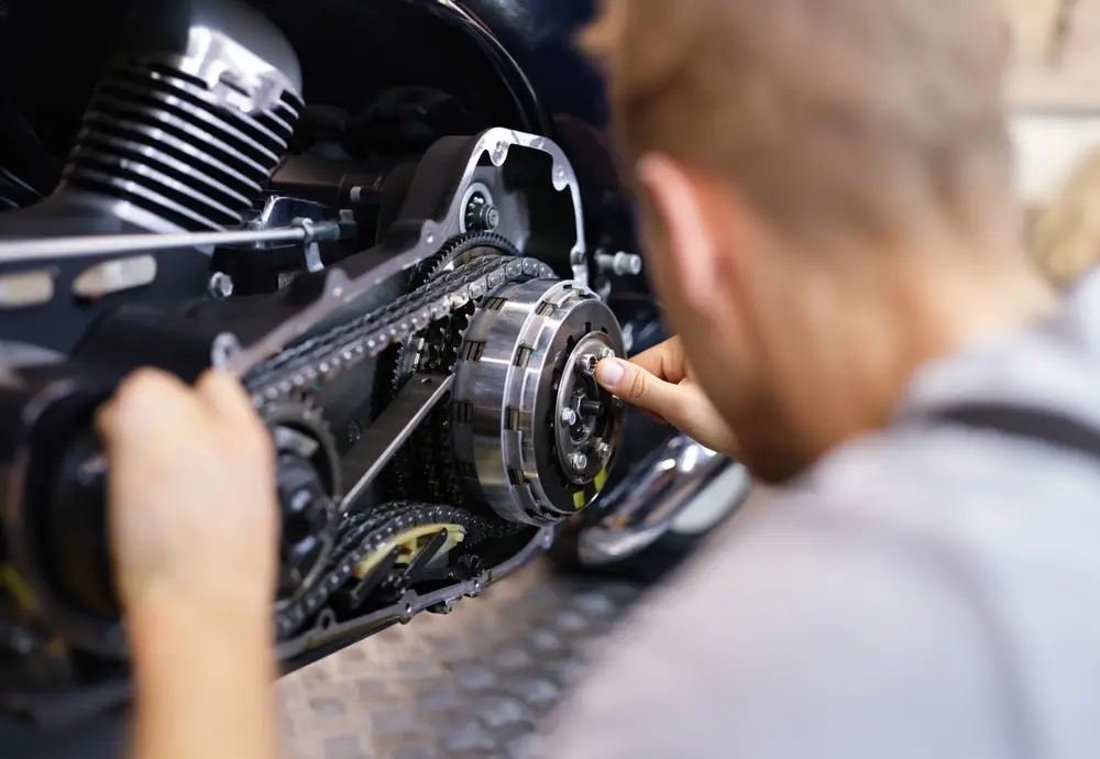 Mecanico desfocado avaliando corrente de uma moto para matéria sobre como cuidar dessa peça.