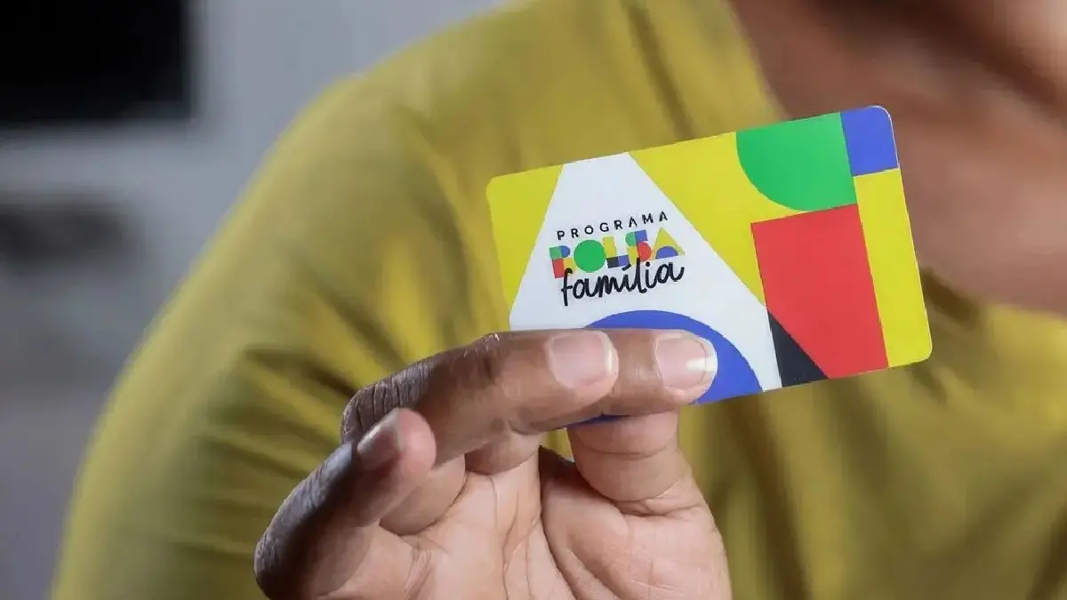 Pessoa segurando um cartão do programa Bolsa Família, que promove benefícios sociais para famílias de baixa renda no Brasil.