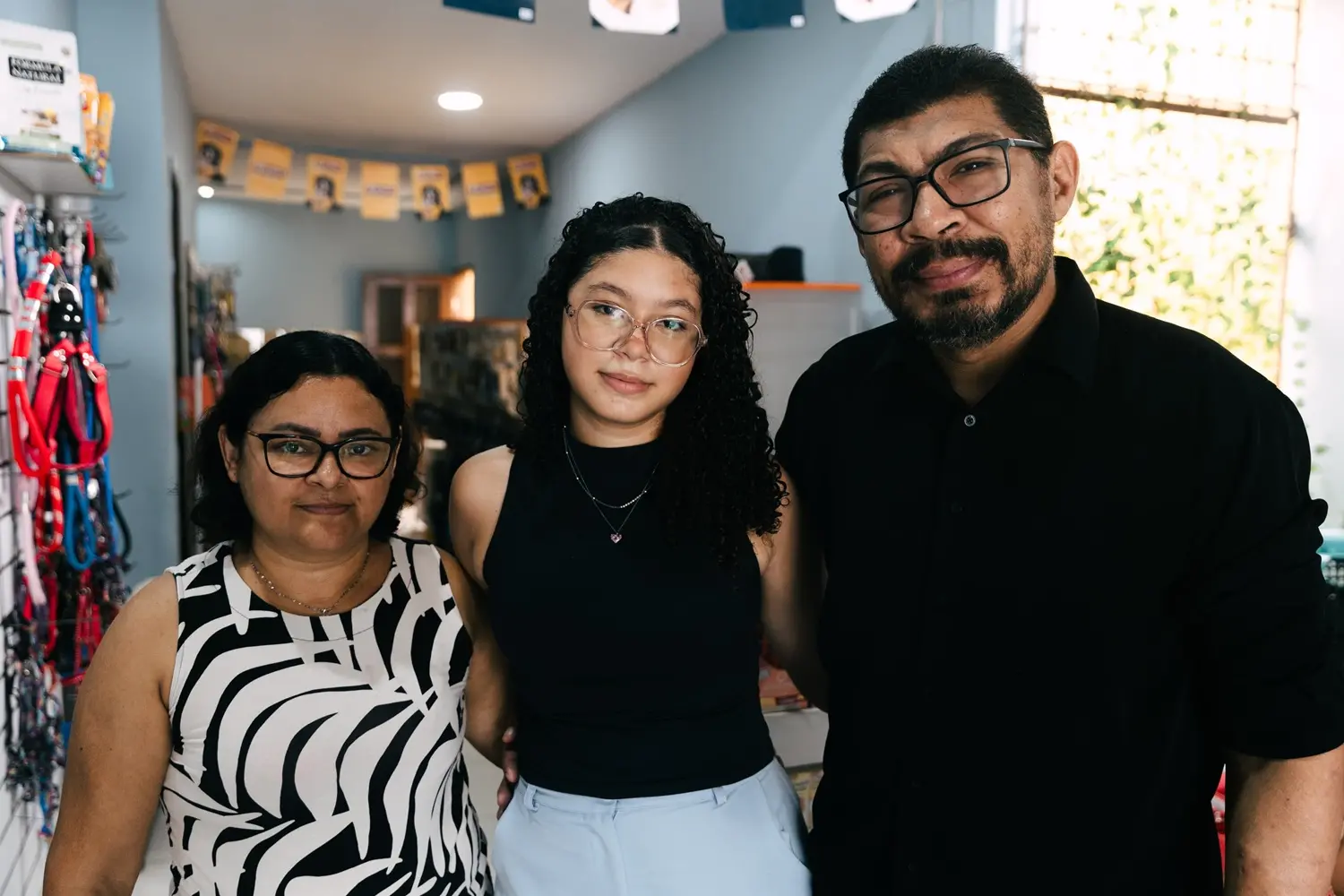Tatiane, Thays e Tiago. Ao fundo, a casa de rações montada em casa.