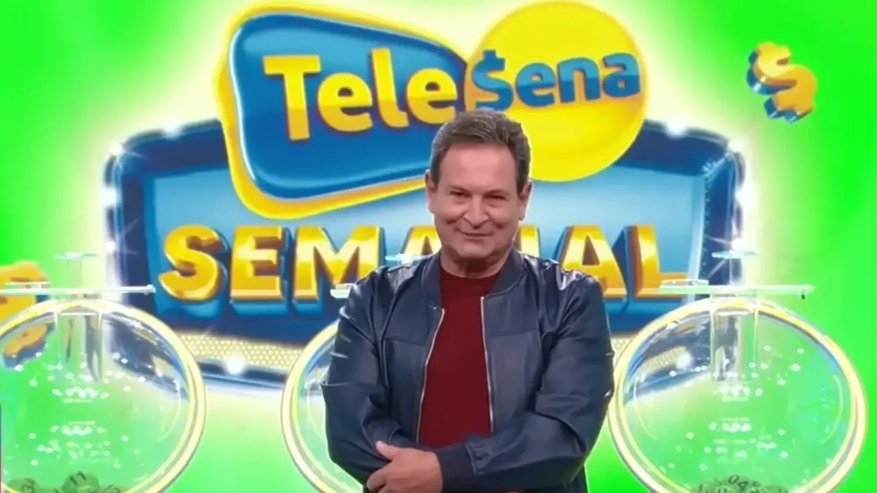 Na imagem, fotografia de estúdio do apresentador Luís Ricardo, um homem de pele clara e cabelos curtos, sorrindo para a câmera. Ele usa uma jaqueta de couro sintético azul escuro e camiseta vermelha escura. O plano de fundo exibe a marca 'Tele Sena Semanal' em letras coloridas dentro de formas geométricas estilizadas. À esquerda e à direita do apresentador, globos de sorteio transparentes contêm bolinhas verdes numeradas. A iluminação é brilhante, típica de programas de auditório.