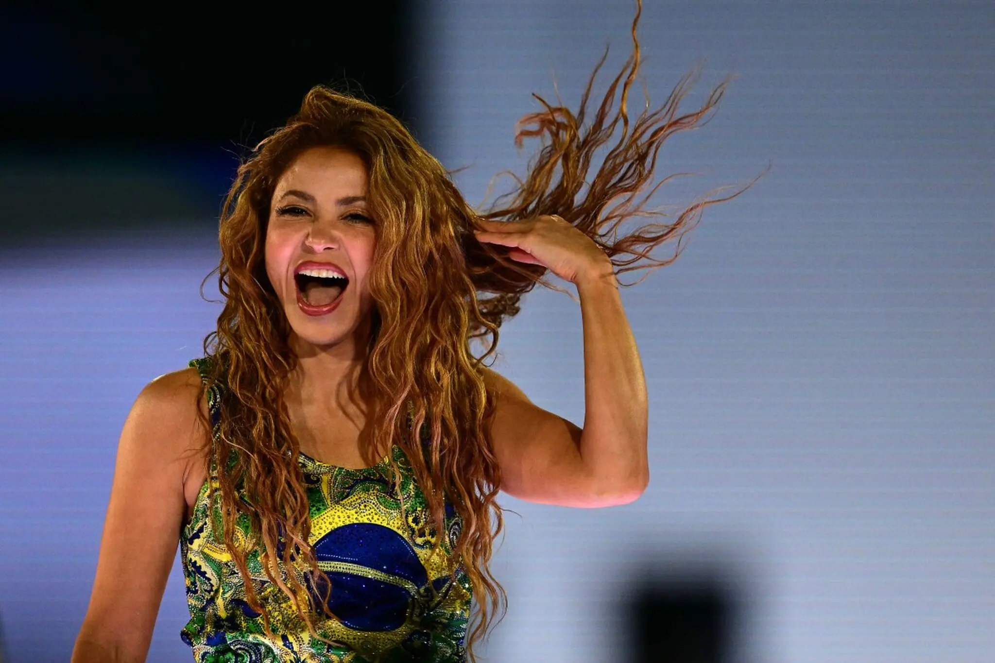 Close do rosto de Shakira, rindo e segurando o cabelo, em show no Rio de Janeiro.