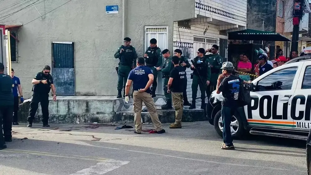 Polícia Militar do Ceará e equipe da perícia investigam cena de crime em rua residencial no bairro Quintino Cunha, em Fortaleza, com viatura estacionada e área isolada por fita após ocorrência com vítima ao chão.