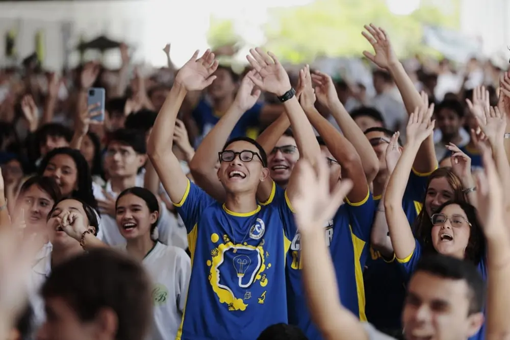 imagem de alunos da rede pública fardados e com os braços para cima em comemoração.