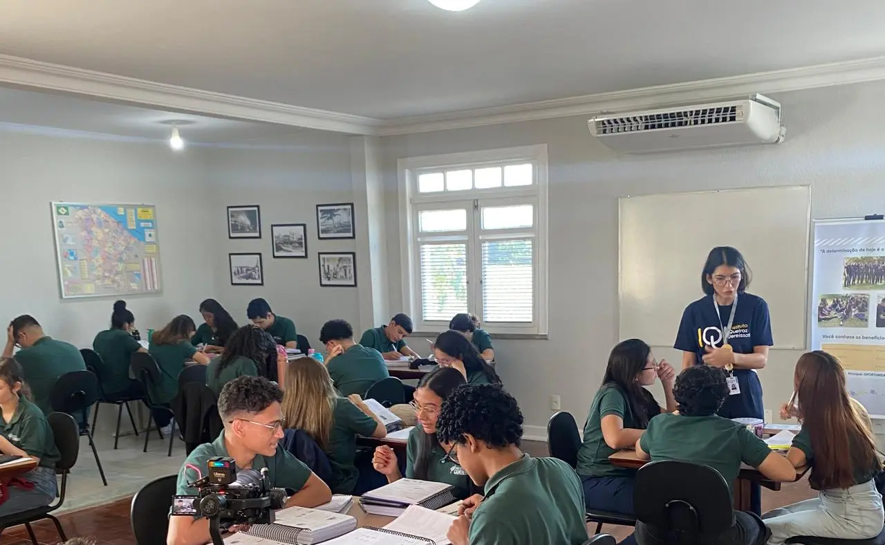 imagem de sala de aula com pessoas sentadas em mesas durante curso.