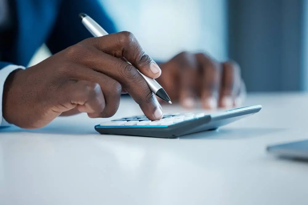 Tela de celular exibe página da Receita Federal sobre a declaração do Imposto de Renda 2026 no portal Gov.br. Ao fundo, aparece desfocado o logotipo da campanha do IRPF 2026.