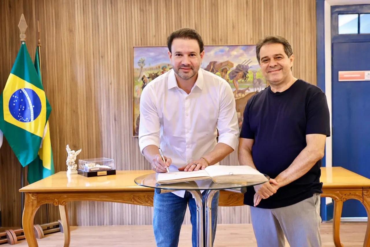 O vereador Leo Couto assina documento ao lado do prefeito Evandro Leitão.