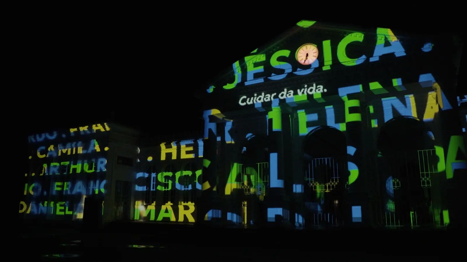 Imagem dos nomes das vítimas projetados na fachada da Estação das Artes para matéria sobre homenagem às vítimas da pandemia.