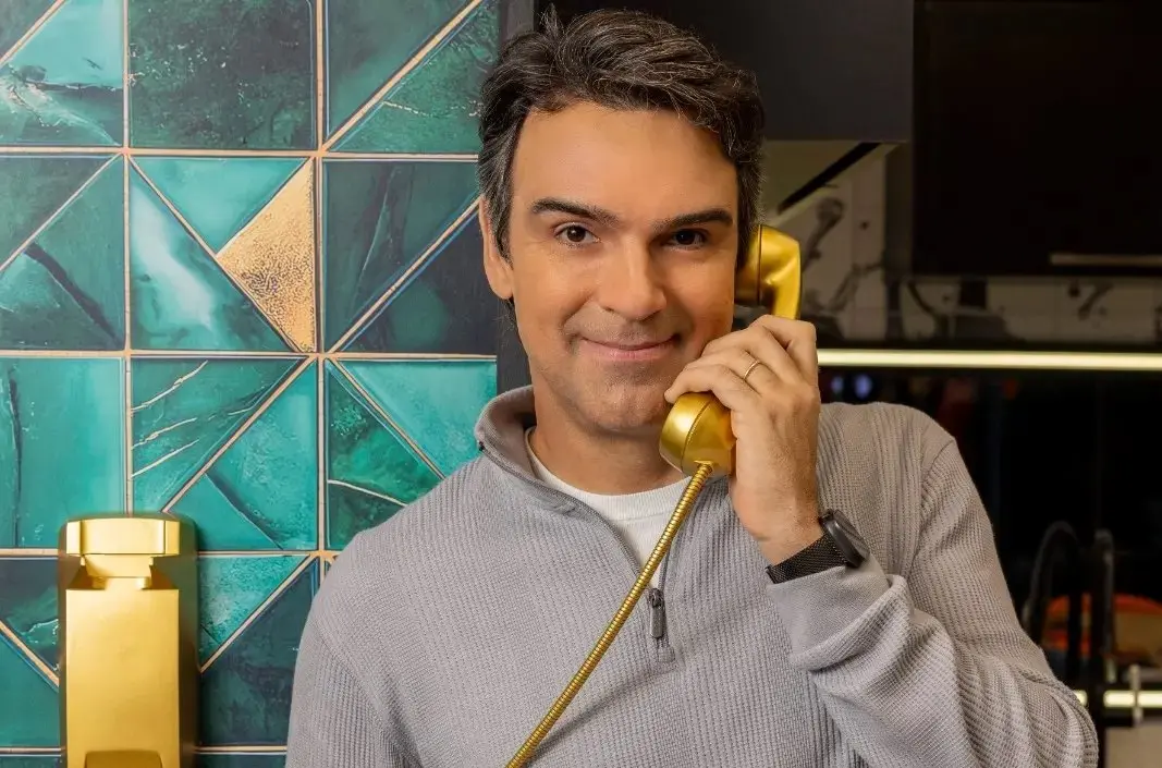Tadeu é um homem alto, branco, de cabelo grisalho, e, na foto, ele usa moletom cinza e segura um telefone dourado. Imagem usada em matéria sobre renovação do reality show Big Brother Brasil.