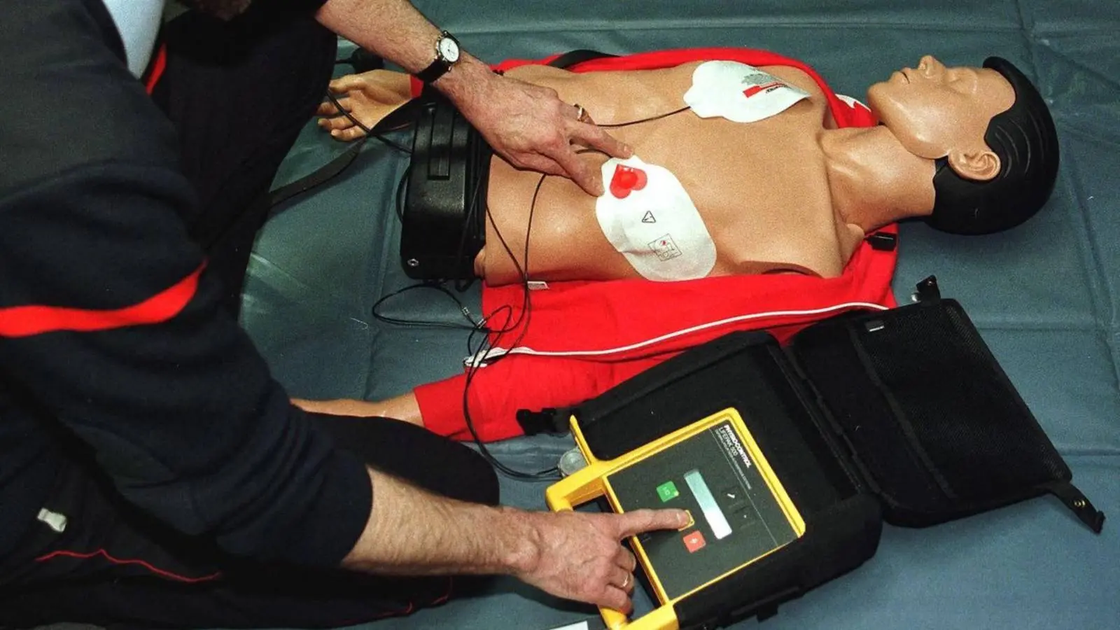 Imagem mostra homem usando um desfibrilador utilizável por pessoas sem formação médica.