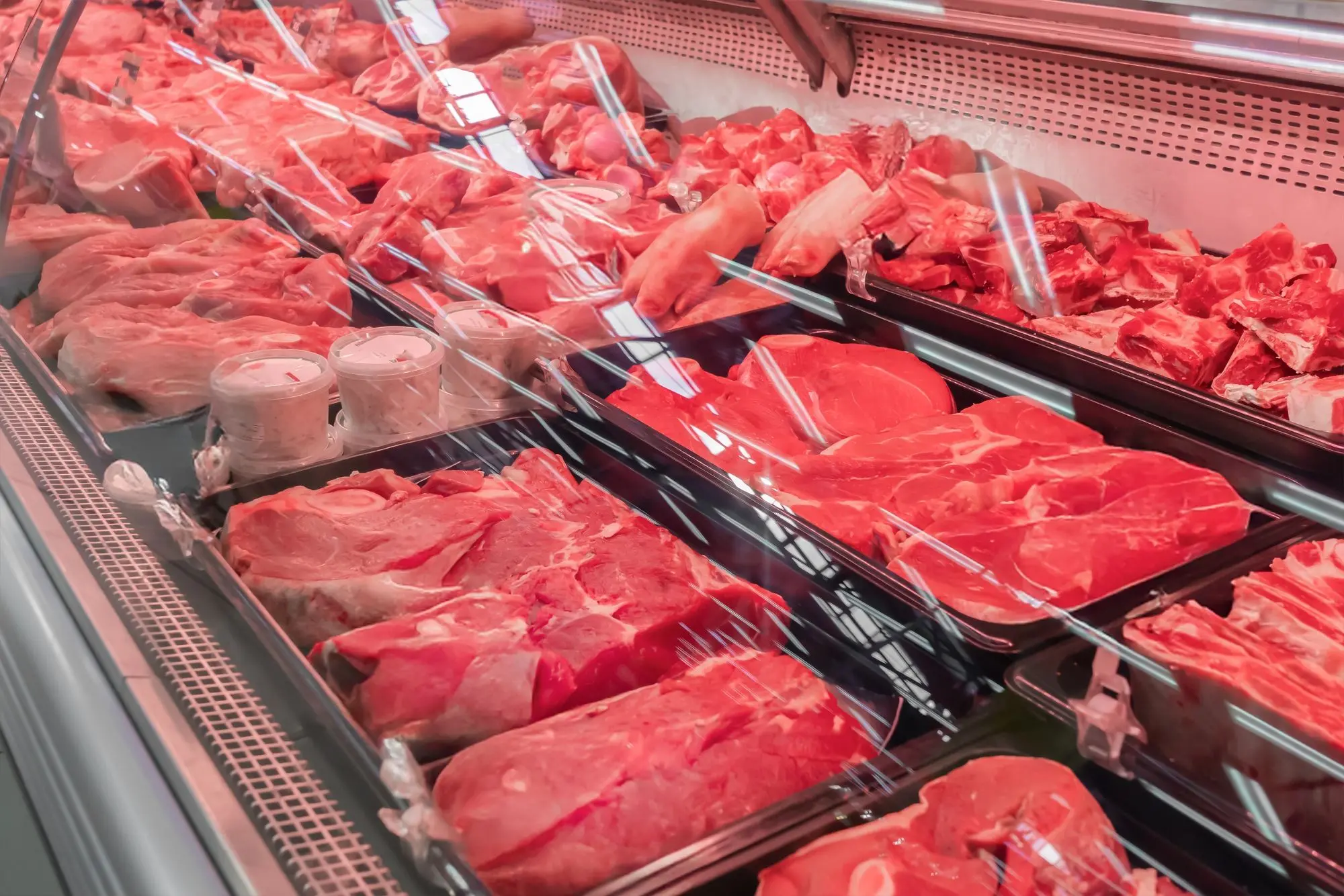 imagem de balcão de açougue com pedaços de carne crua expostos.