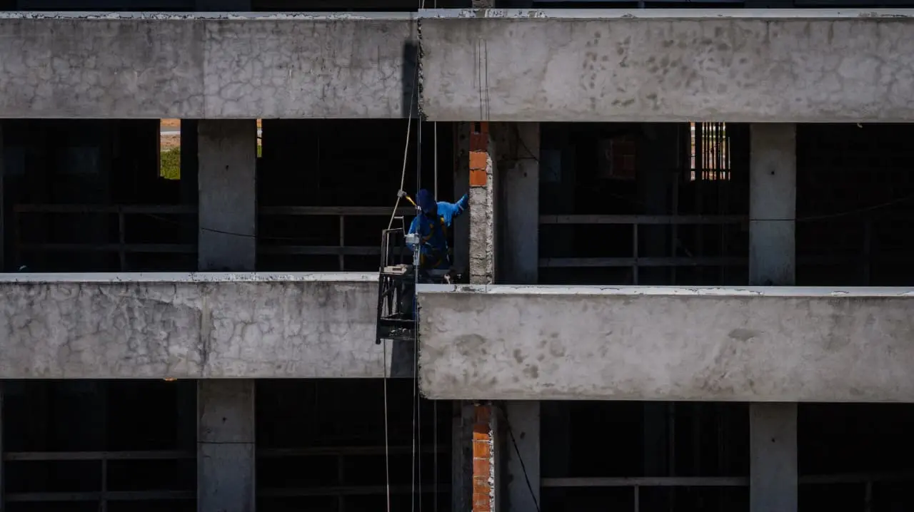 Homem trabalhando em obra de sacada de hotel.