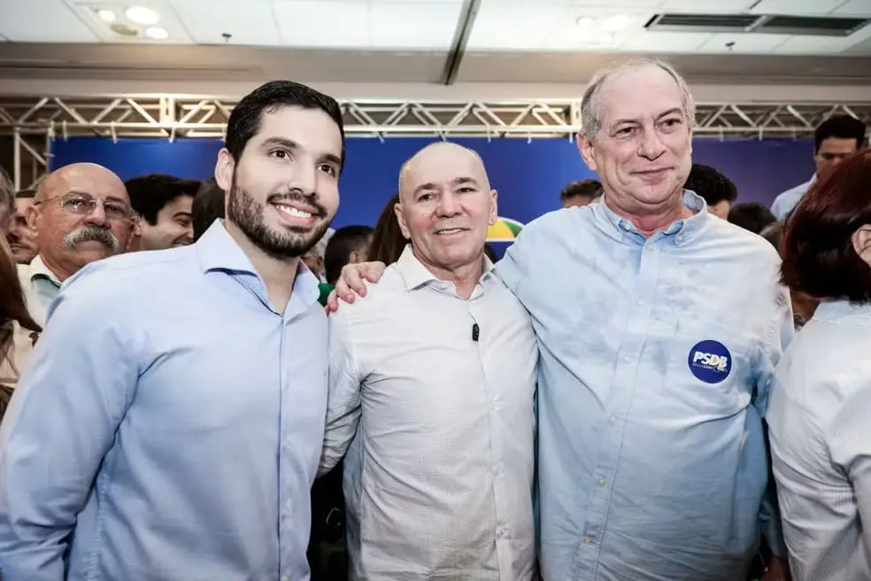 Foto mostra André Fernandes, Pastor Alcides e Ciro Gomes abraçados em evento partidário.