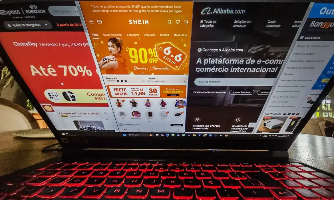 Tela de notebook exibe plataformas internacionais de compras online, como Shein e Alibaba, em imagem sobre importações e comércio eletrônico.