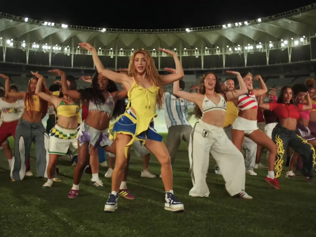 cena do clipe de 'Dai Dai' com Shakira, música oficial da Copa do Mundo de 2026. Imagem mostra a cantora dançando ao lado de bailarinos no Maracanã.