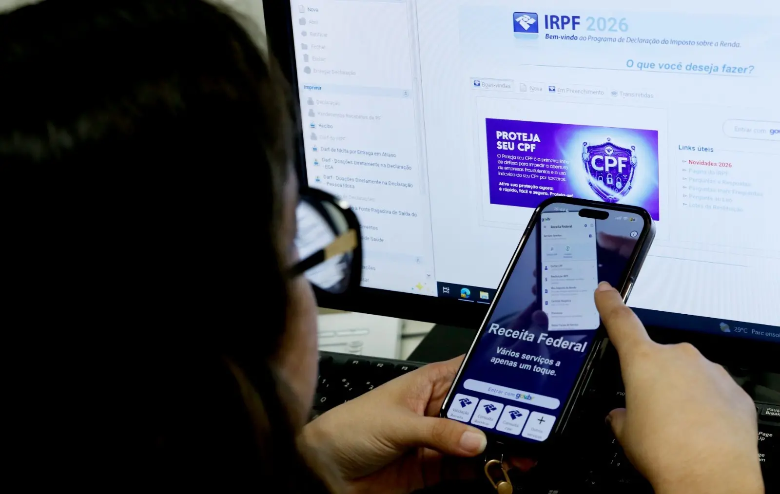 Mulher mexe em celular aberto no site da Receita Federal.