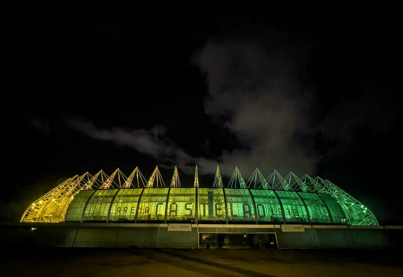 Arena Castelão iluminada com as cores do Brasil.