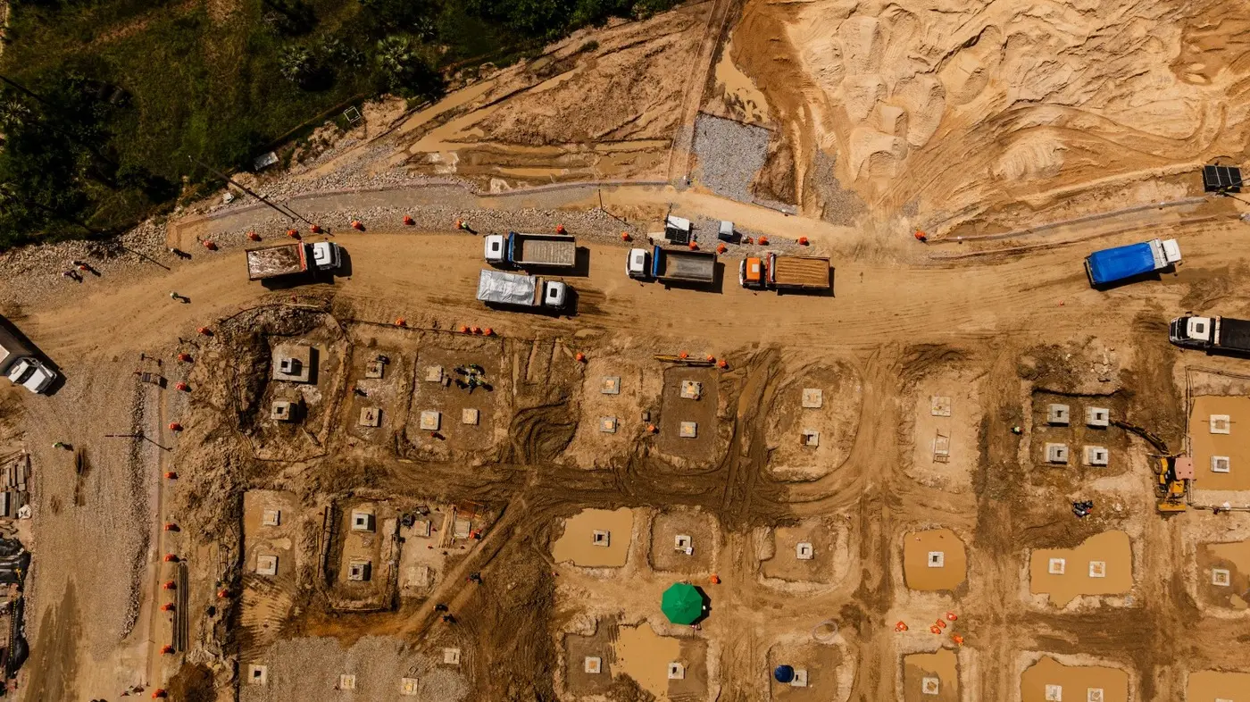 Foto que contém movimentação de caminhões em terreno passando por terraplanagem no futuro Data Center Pecém.