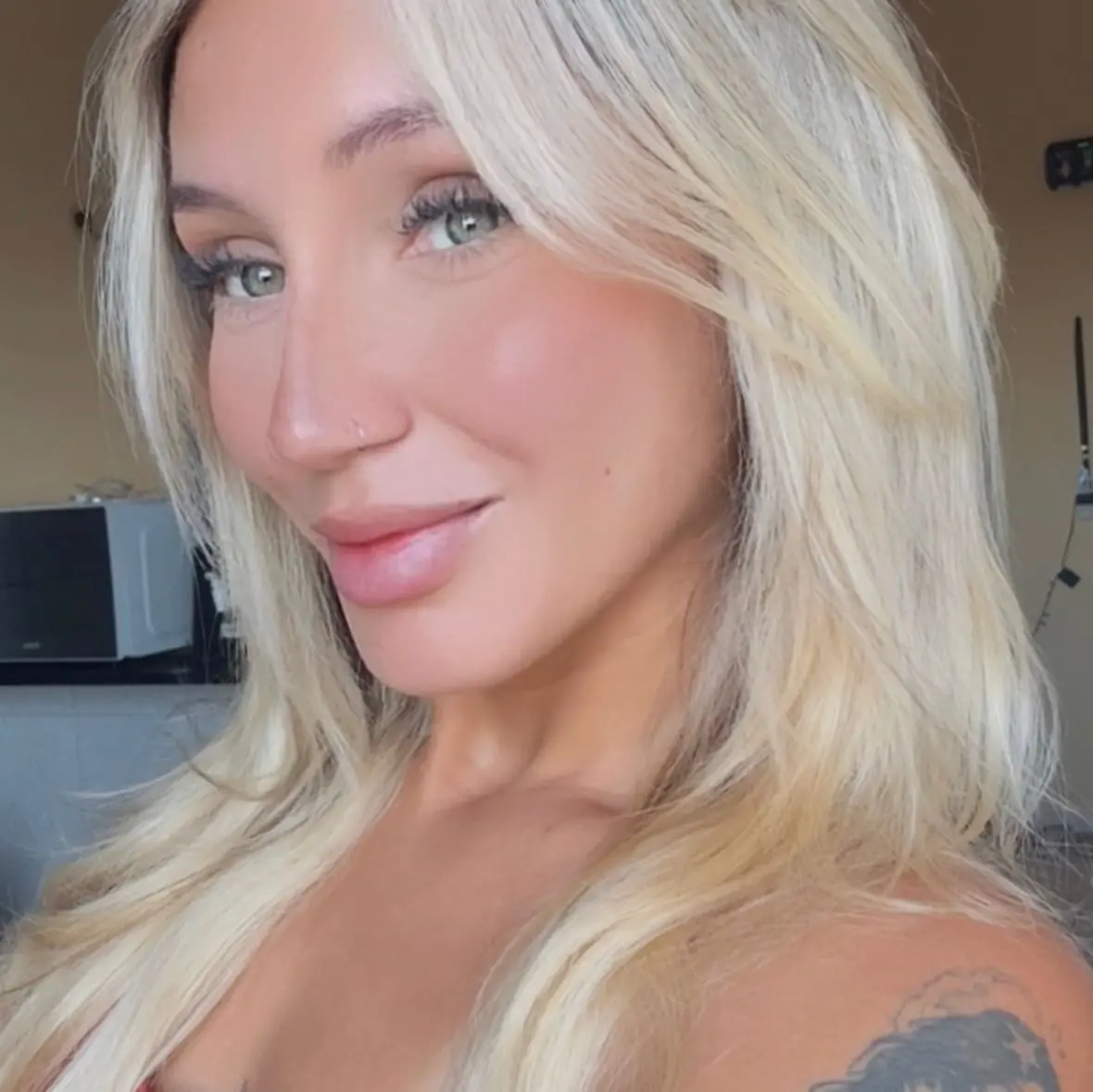 Thays é uma mulher jovem, loira e branca de olhos azuis. Na foto, uma selfie, ela está dando um sorriso de boca fechada.