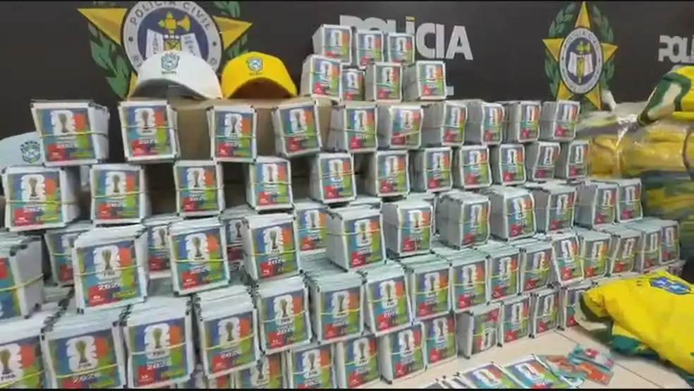 Enxoval de produtos embalados em caixas e latas enfileiradas em uma operação, com banners e identificação ao fundo, em um cenário de apreensão e fiscalização.